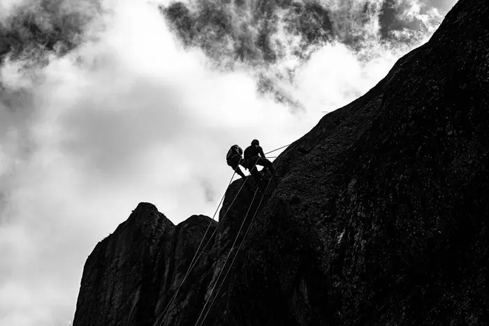 Mountaineers climbing with ropes on a rock face