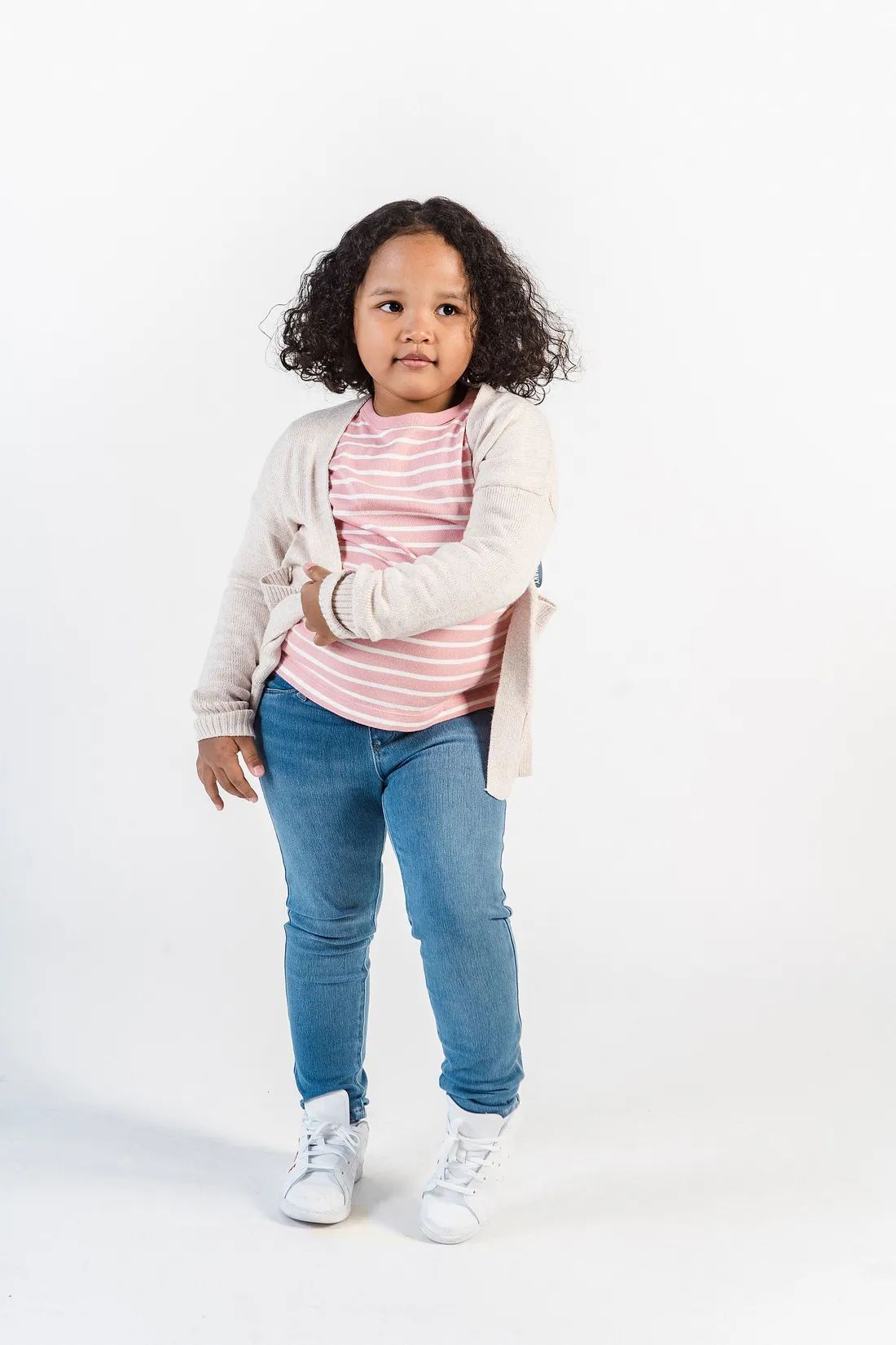 A confident kid wearing a striped shirt and cardigan