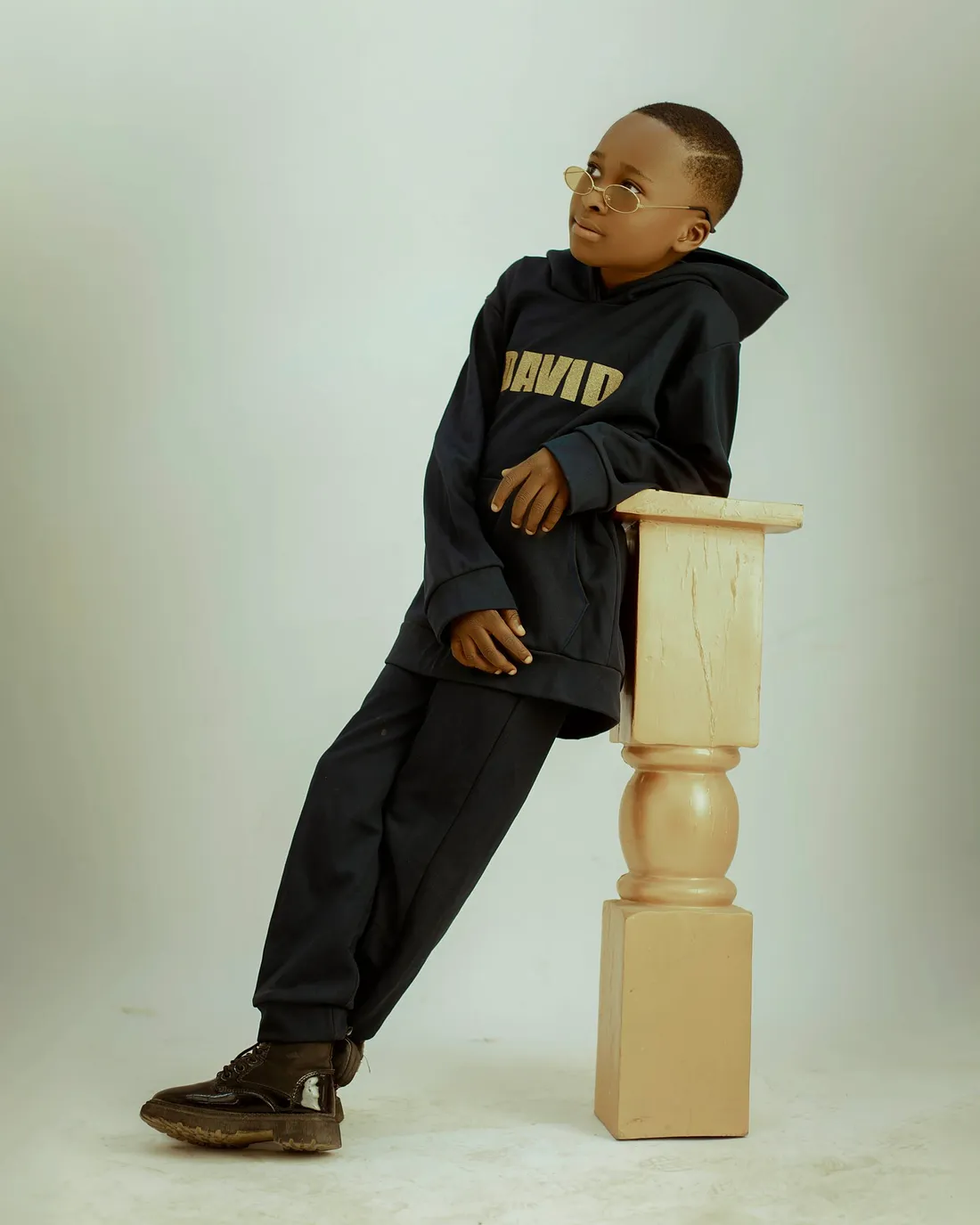 A child wearing a navy jacket, leaning on a pedestal