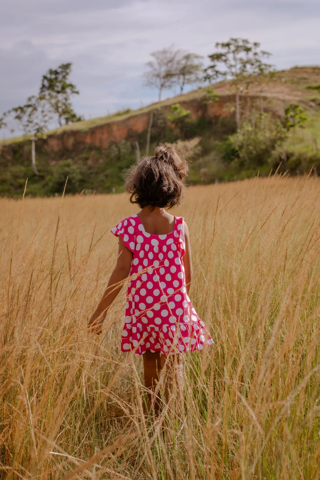 A girl in a flowing dress walking through a field