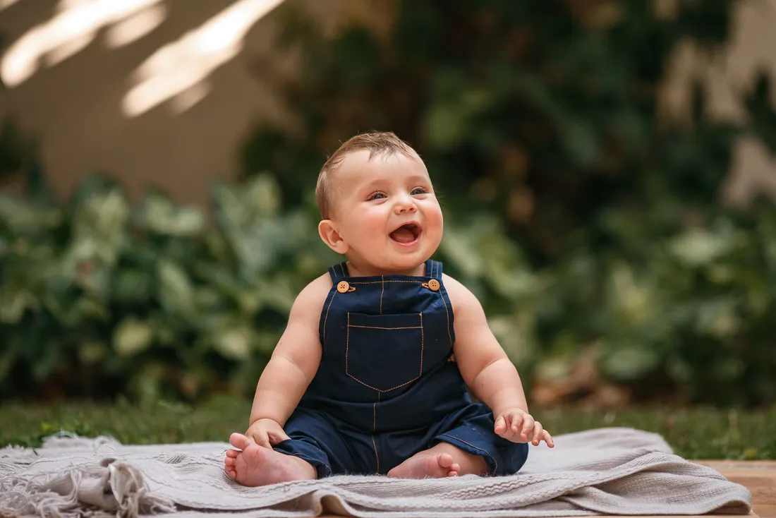 A smiling boy wearing blue overalls