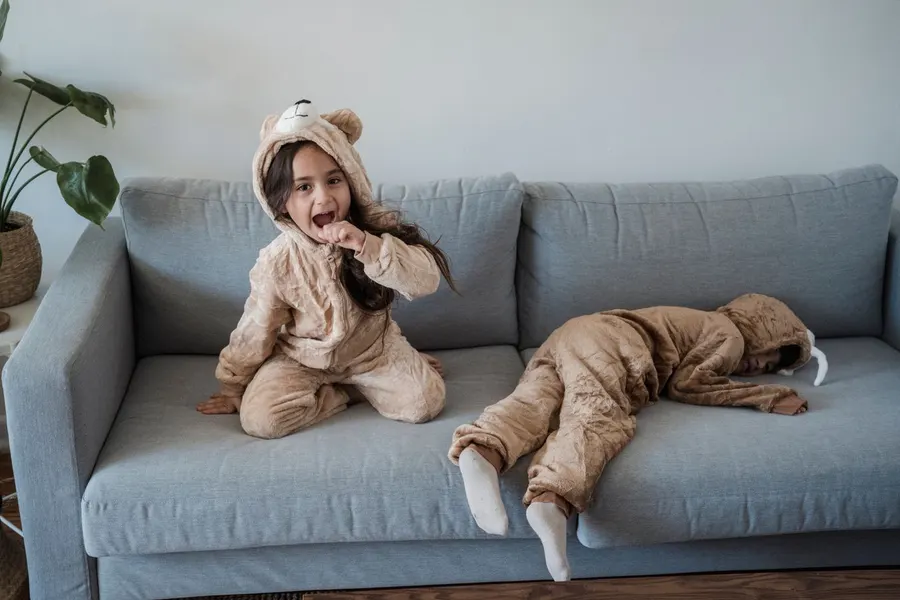 Kids wearing pyjamas playing on a sofa