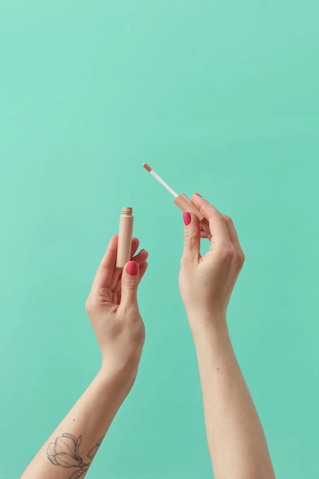 Hands holding a concealer applicator against a pastel blue background
