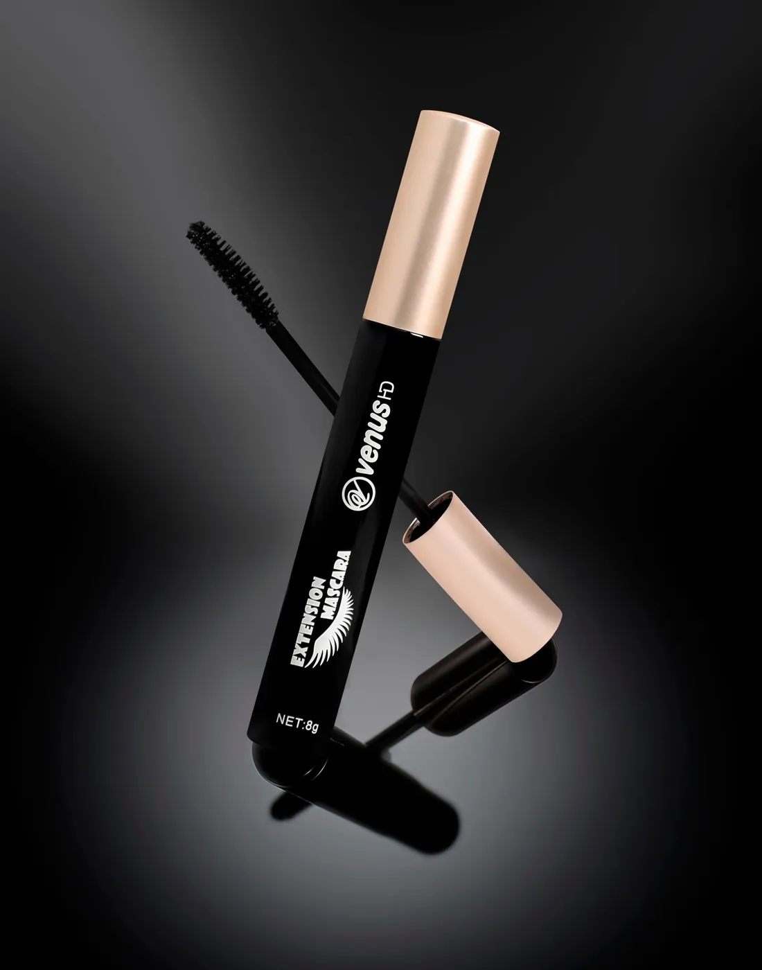 Sleek black mascara tube with a gold cap on a glossy surface