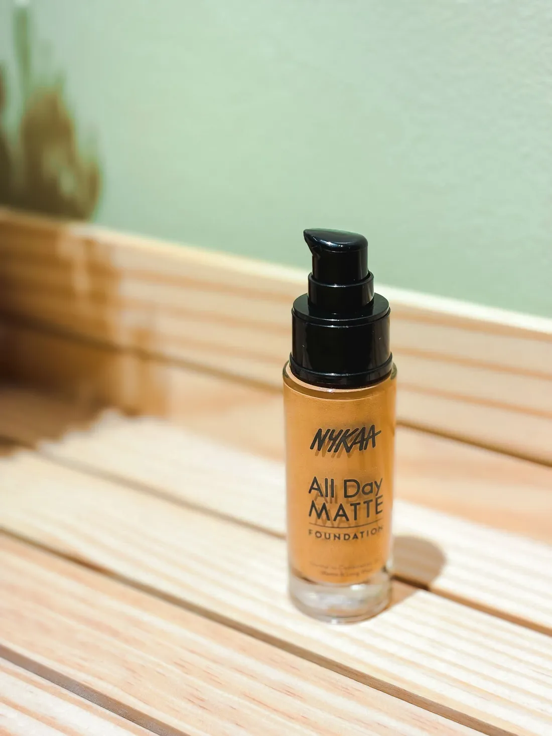Matte foundation bottle on a wooden surface with soft lighting