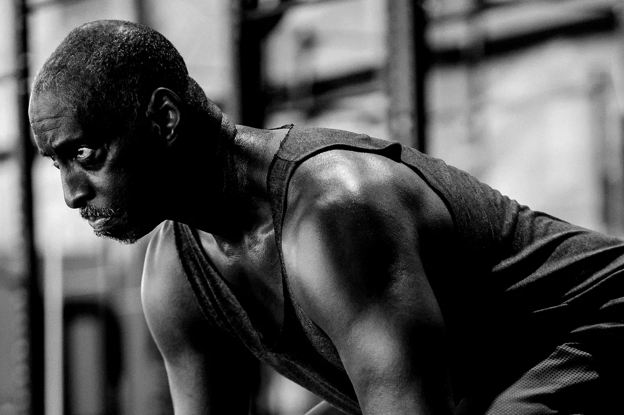 An athlete bent over the bar between conditioning efforts, breathing hard