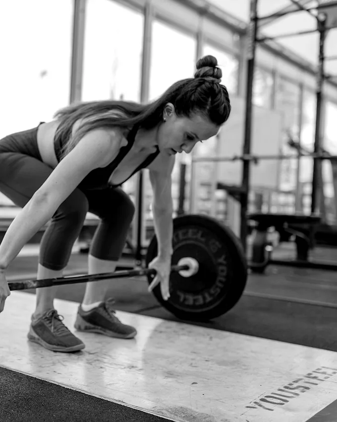 A member setting her position over a loaded bar