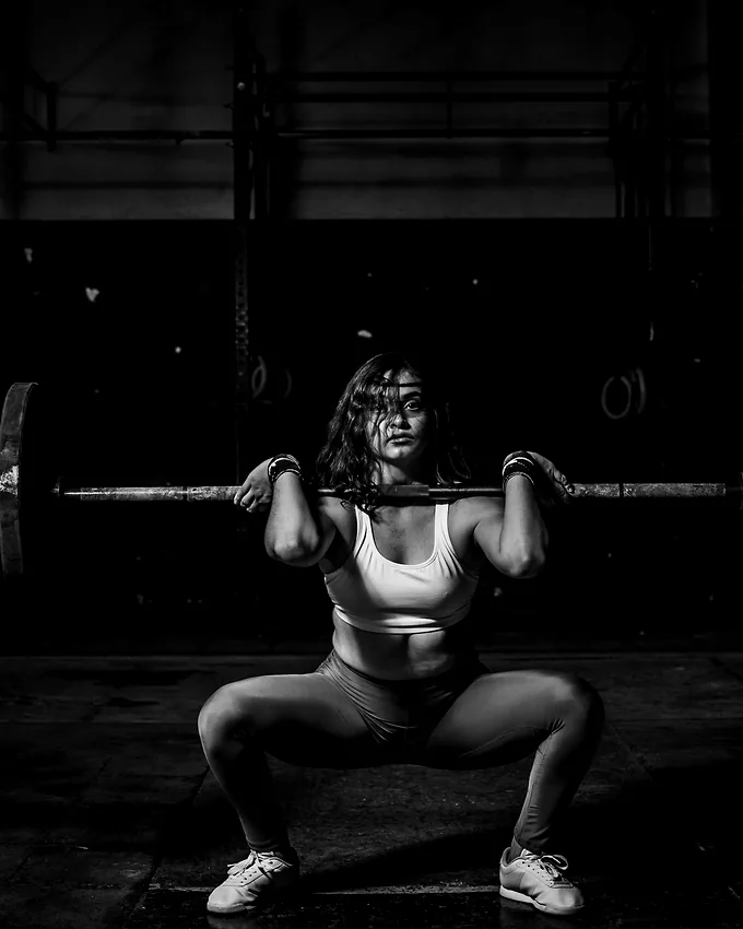 A member squatting under the bar in low light