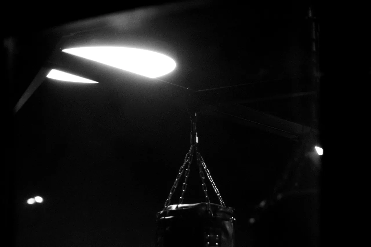A heavy bag hanging in the unlit corner of the studio