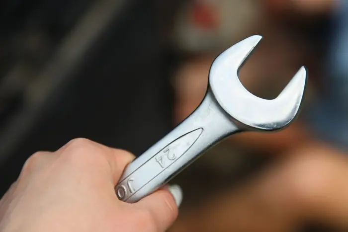 Close-up of a hand holding a metal wrench in the workshop