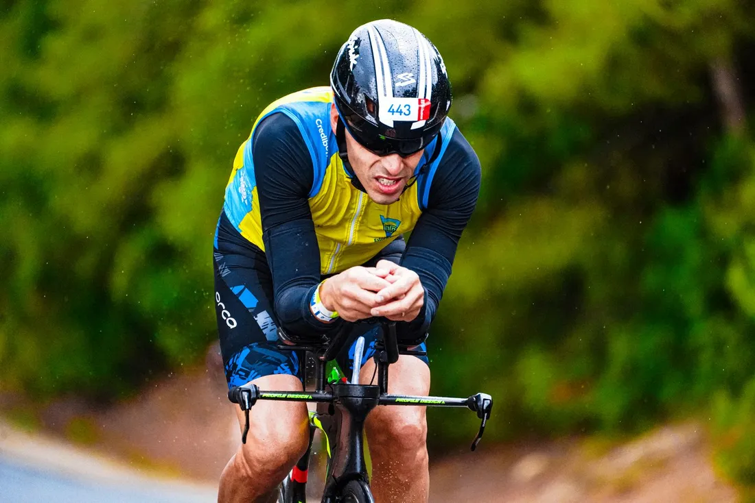 Focused cyclist riding a road bike beside a forest