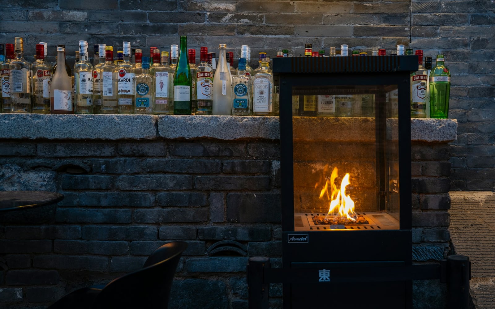 The Fire Lounge at night: deep chairs, a long bar and firelight on timber