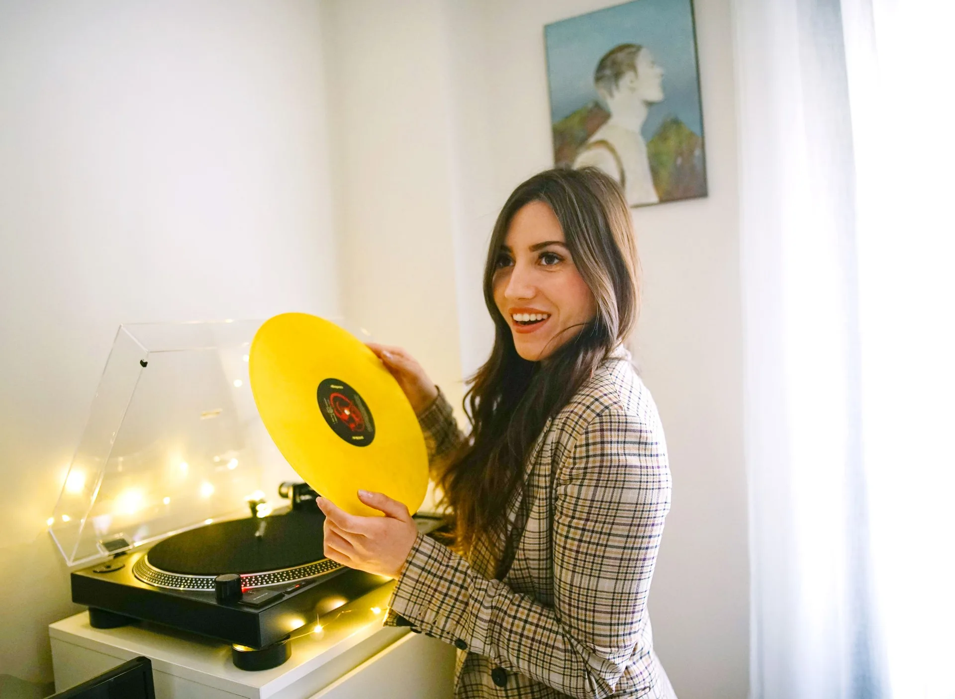A customer pulling a yellow vinyl record off a turntable, smiling