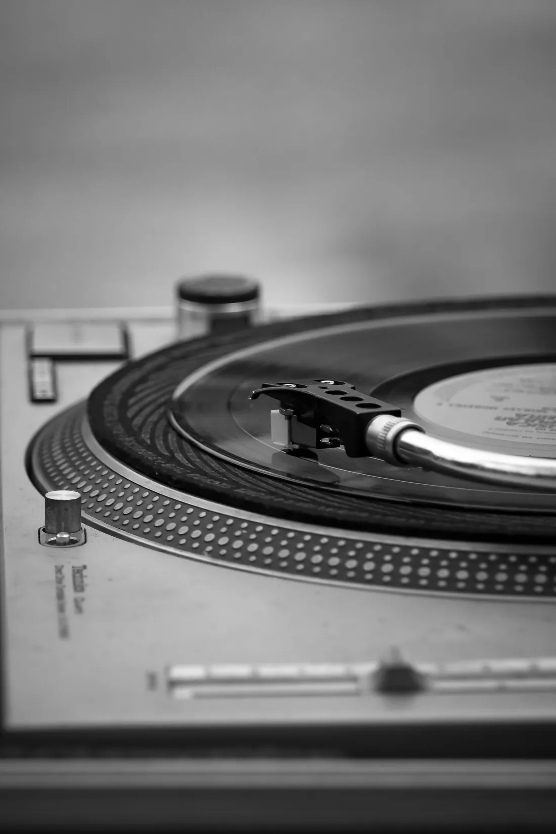 Black and white close-up of a vintage turntable playing a vinyl record
