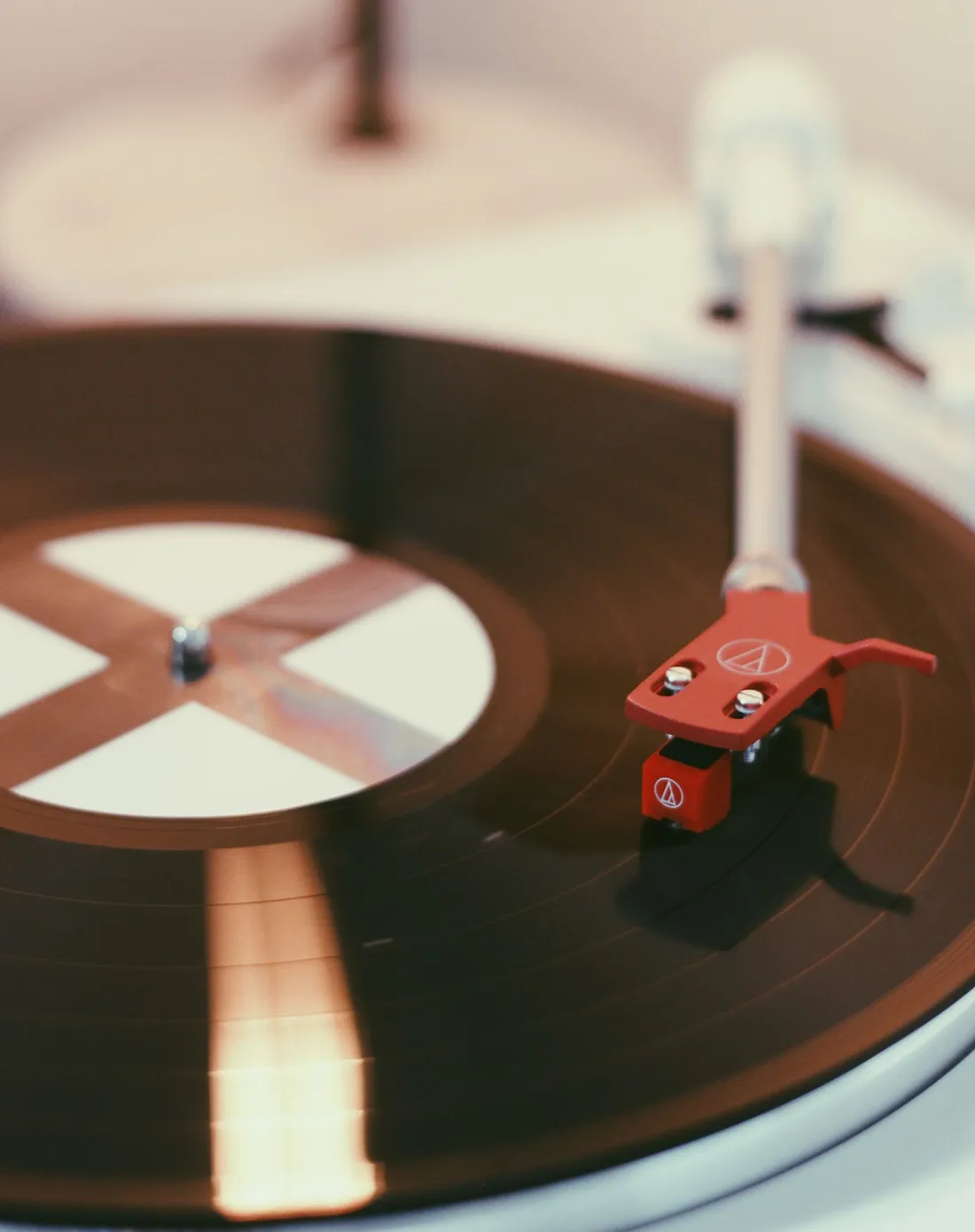 Close-up shot of a vinyl record on a turntable with a red cartridge