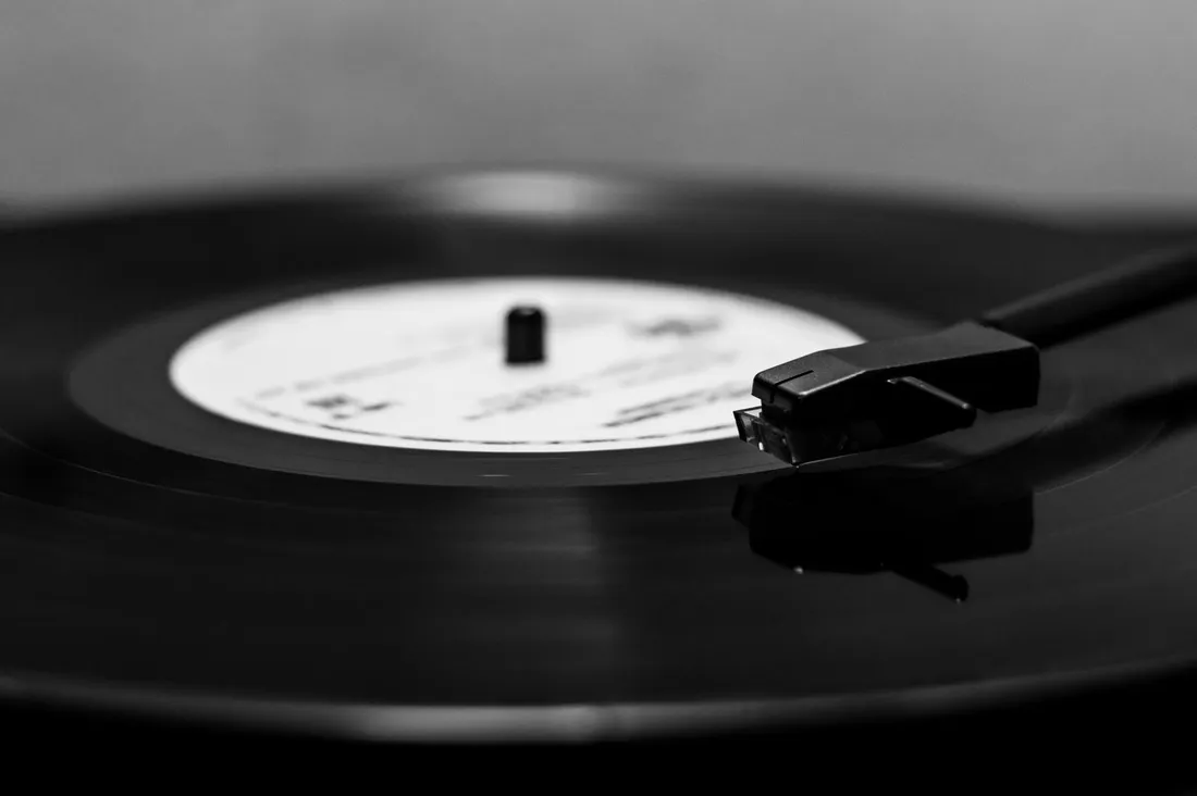 Black and white close-up of a black vinyl record playing on a turntable